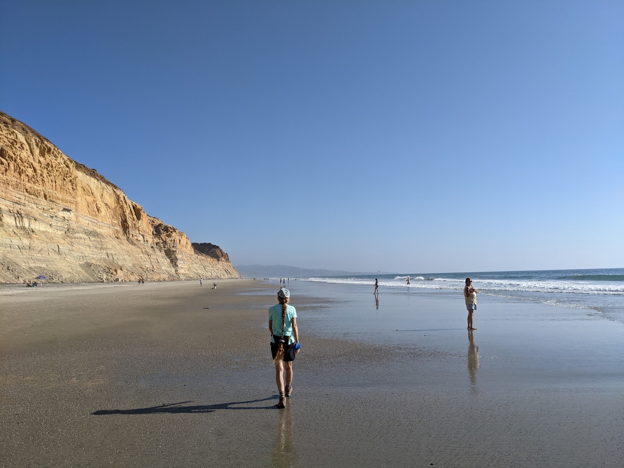 Hiker walking along the beach at Torrey Pines State Natural Reserve in San Diego County 