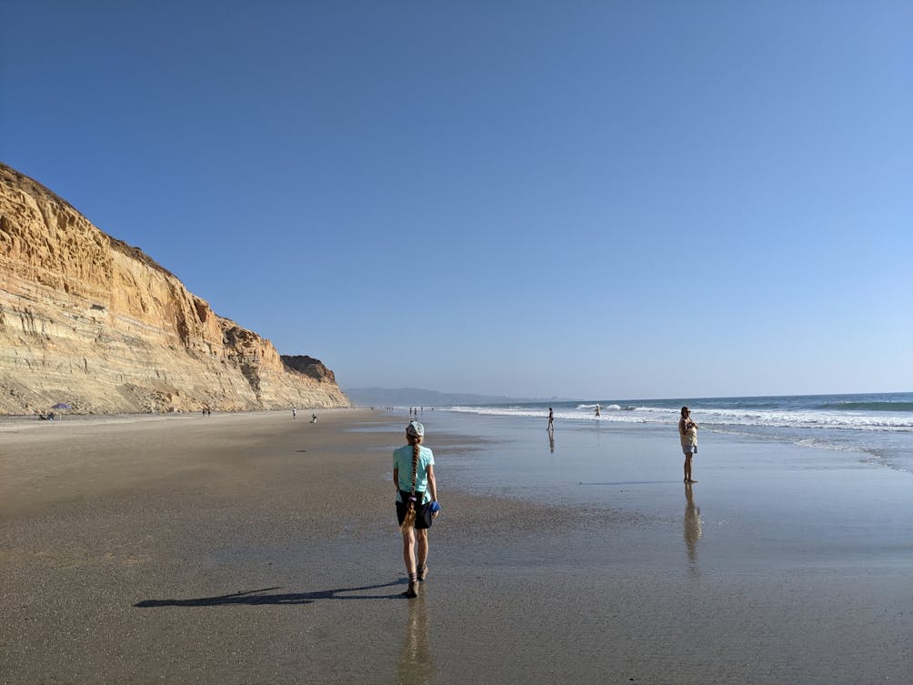 Hiker walking along the beach at Torrey Pines State Natural Reserve in San Diego County 