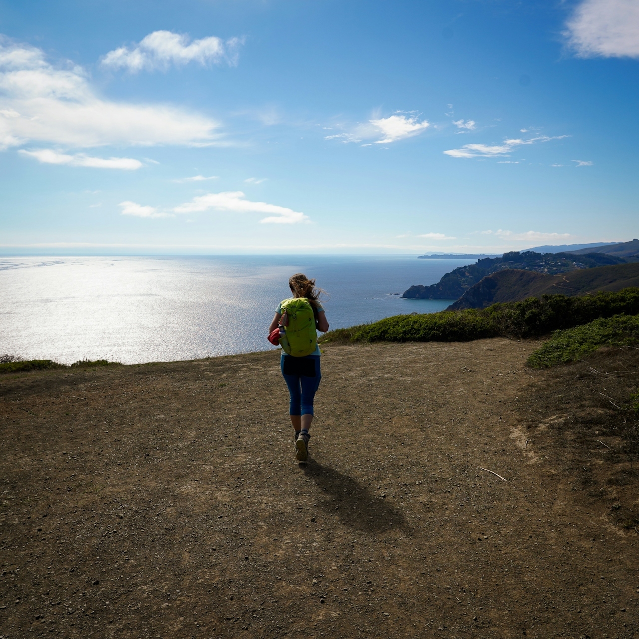 Woman standing at the top of Coyote Ridge and looking out to the Pacific ocean on the Coastal Trail in the Marin Headlands 