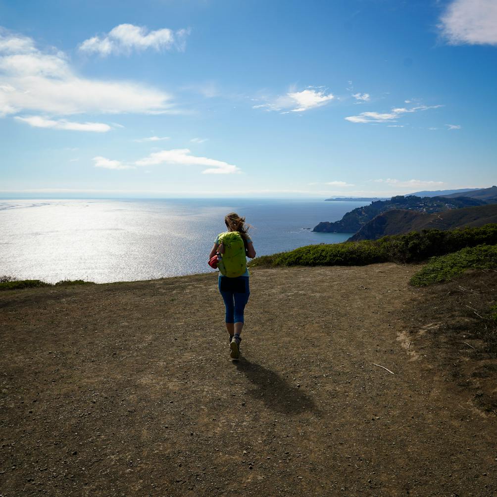 Woman standing at the top of Coyote Ridge and looking out to the Pacific ocean on the Coastal Trail in the Marin Headlands 