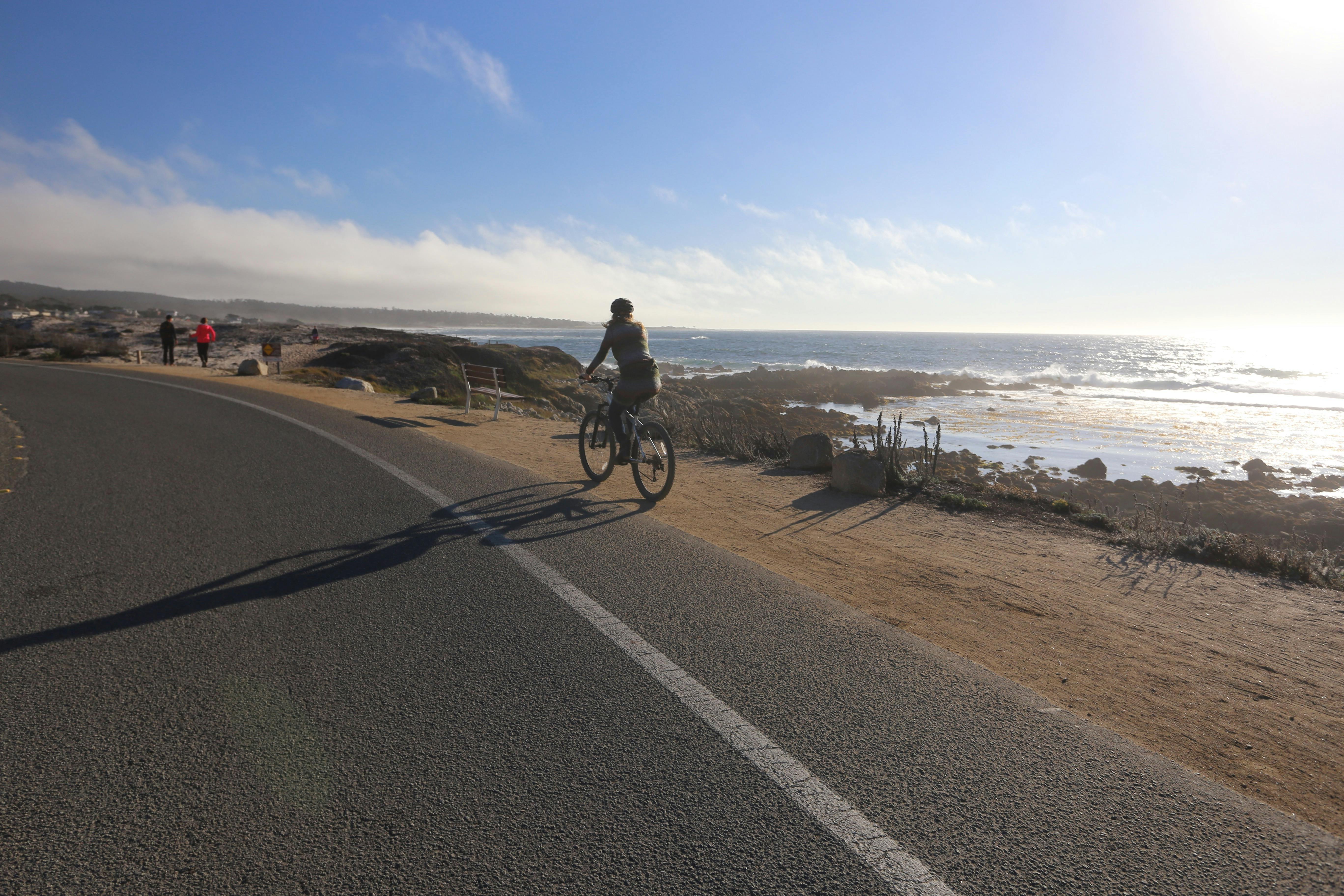 Woman on a bike riding alongside the coast and ocean in Monterey 