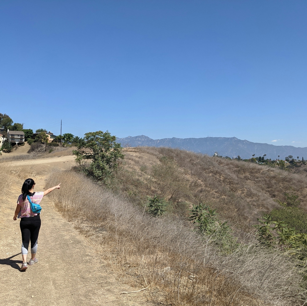 Hiker on trail pointing to surrounding hills at Elephant Hill Open Space in Los Angeles 