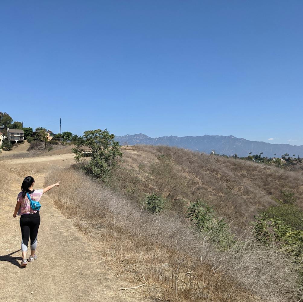 Hiker on trail pointing to surrounding hills at Elephant Hill Open Space in Los Angeles 