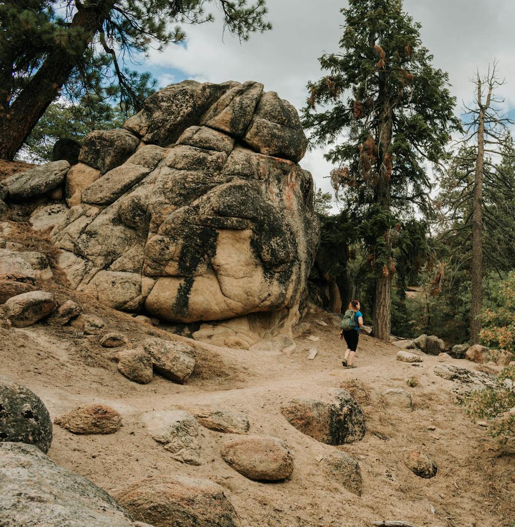 Hiker passing large boulder rock on Grays Peak Trail in Big Bear Lakes Southern California 