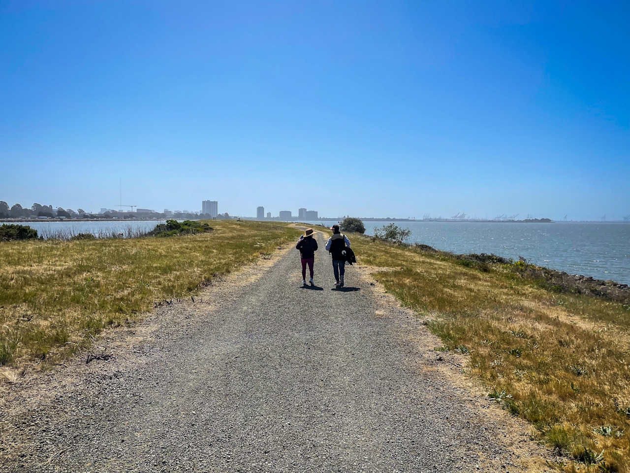 Two people walking along the wide open trail at Brickyard Cove in McLoughlin Eastshore State Park 