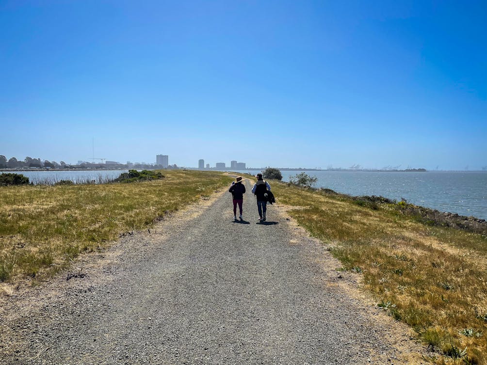 Two people walking along the wide open trail at Brickyard Cove in McLoughlin Eastshore State Park 