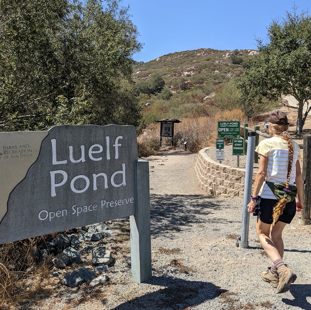 Hiker going buy Luelf Pond entrance sign in northern San Diego County 