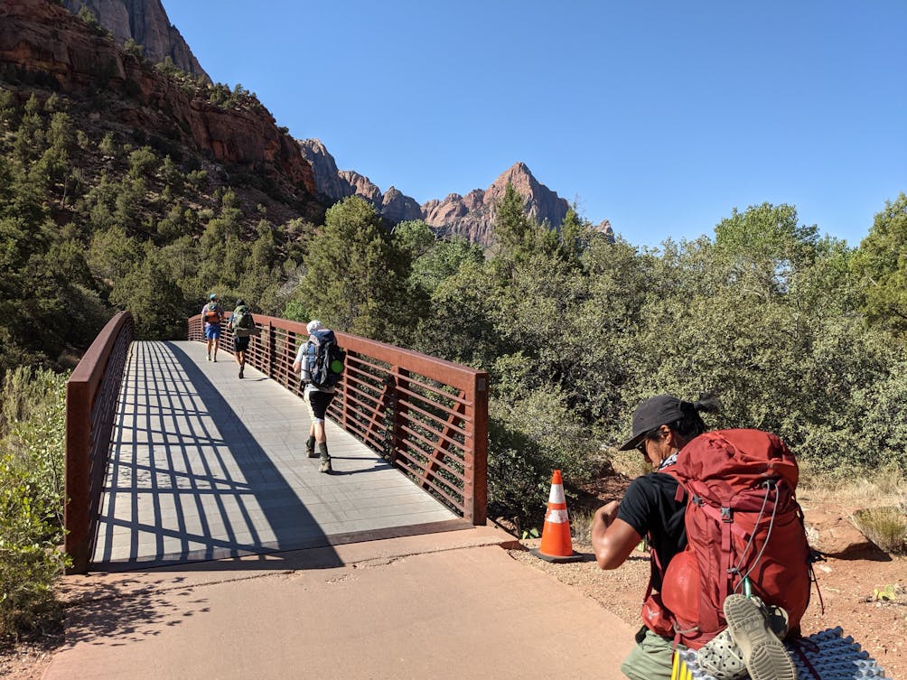 Hikers crossing a bridge on a backpacking trip in Zion National Park.