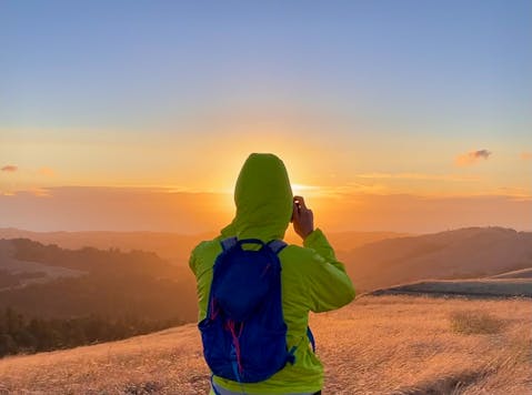 Hiker taking a photo of sunset at Russian Ridge Open Space Preserve