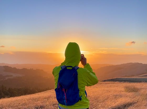 Hiker taking a photo of sunset at Russian Ridge Open Space Preserve 