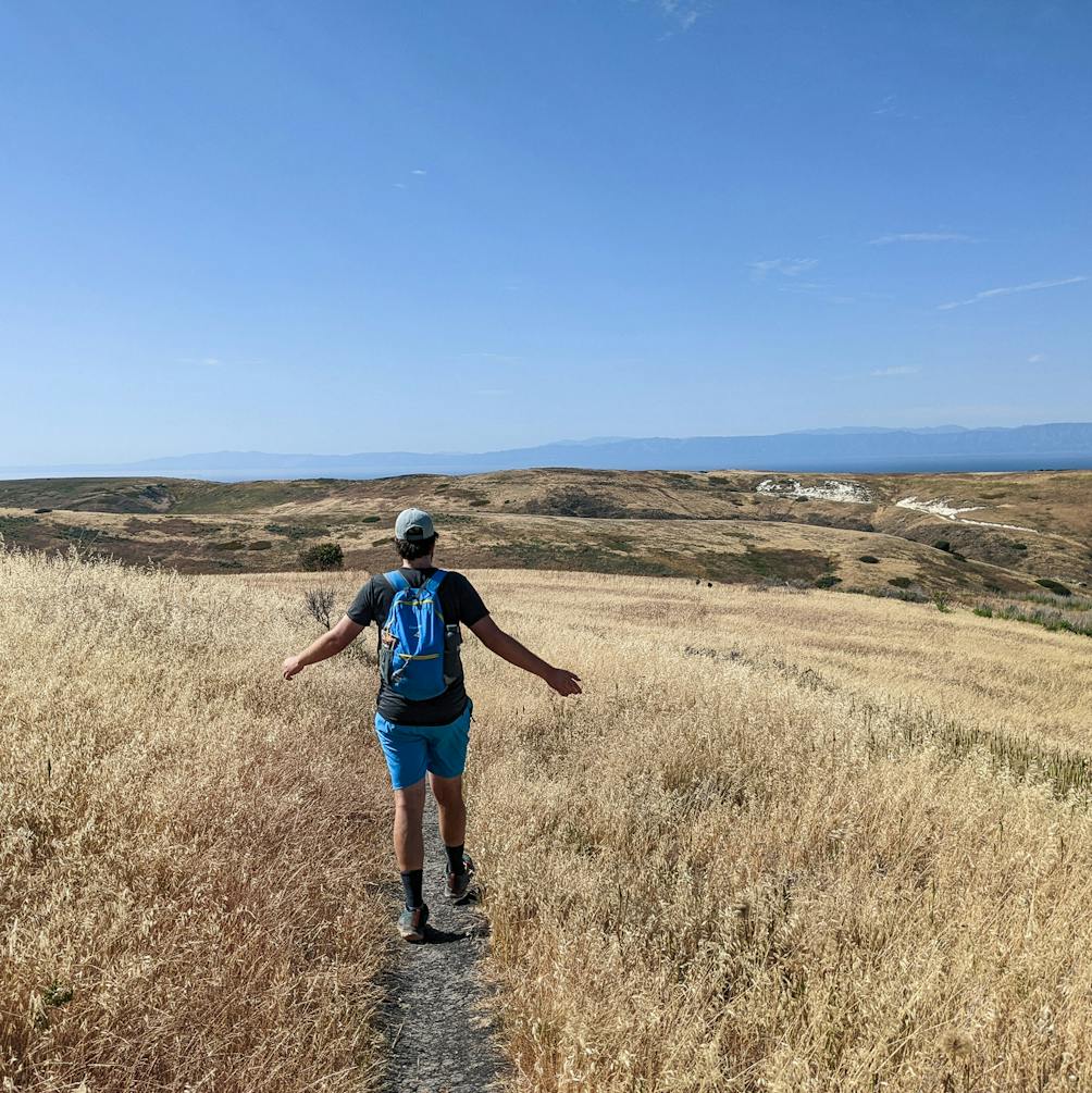 Person hiking with their arms outstretched enjoying the trail and scenery on Santa Cruz Island Channel Islands National Park 