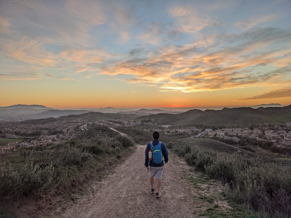 Hiker walking a wide open hiking trail at sunset with huge sky and mountain views in Simi Valley 