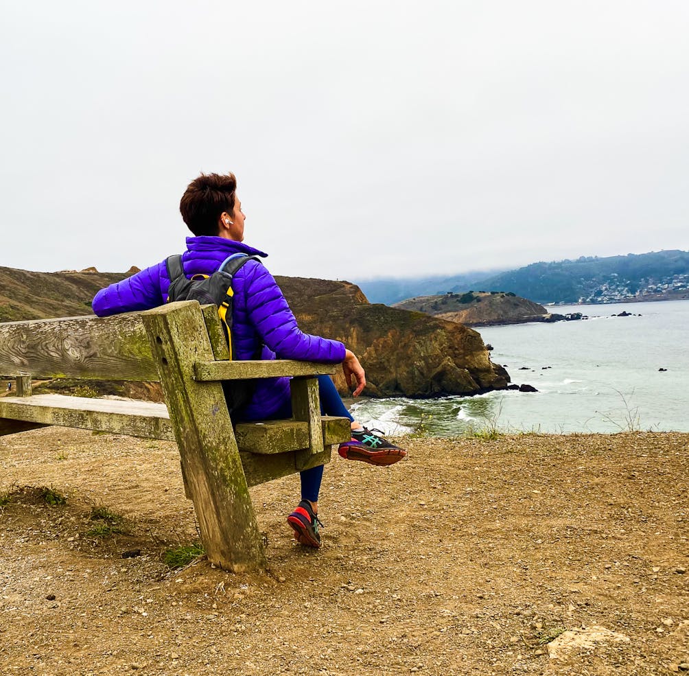Hiker sitting on bench overlooking the Pacific on Mori Point Loop in Pacifica