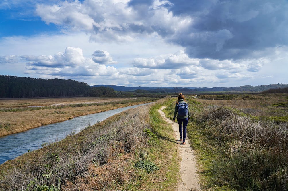 Woman walking alongside the water at Pescadero Marsh Preserve