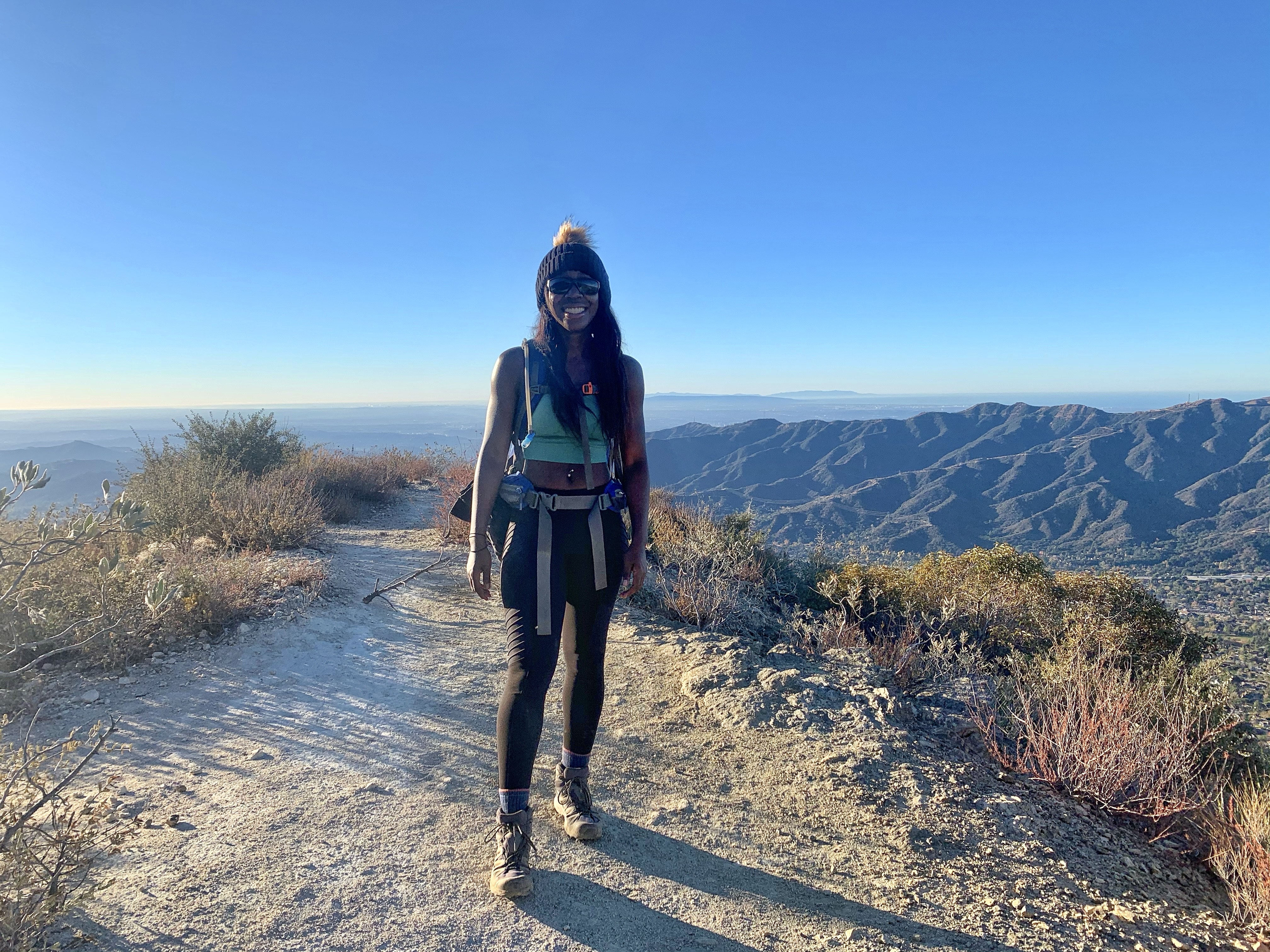 Woman smiling at the peak of Mount Lukens overlooking the San Gabriel Mountains 