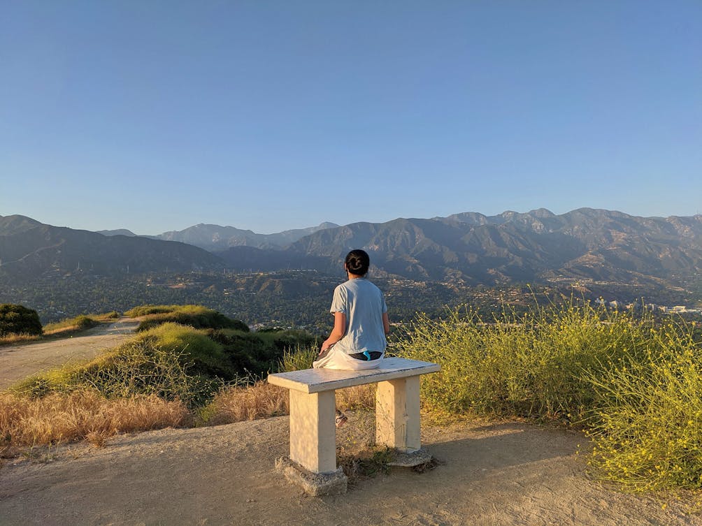 Hiker at a bench overlooking the mountain scenery at Cherry Creek Canyon Park in Los Angeles