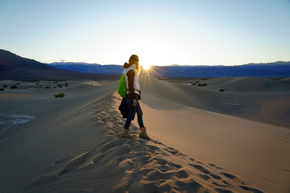 Woman on sand dune at Mesquite Flat at sunset in Death Valley National Park 
