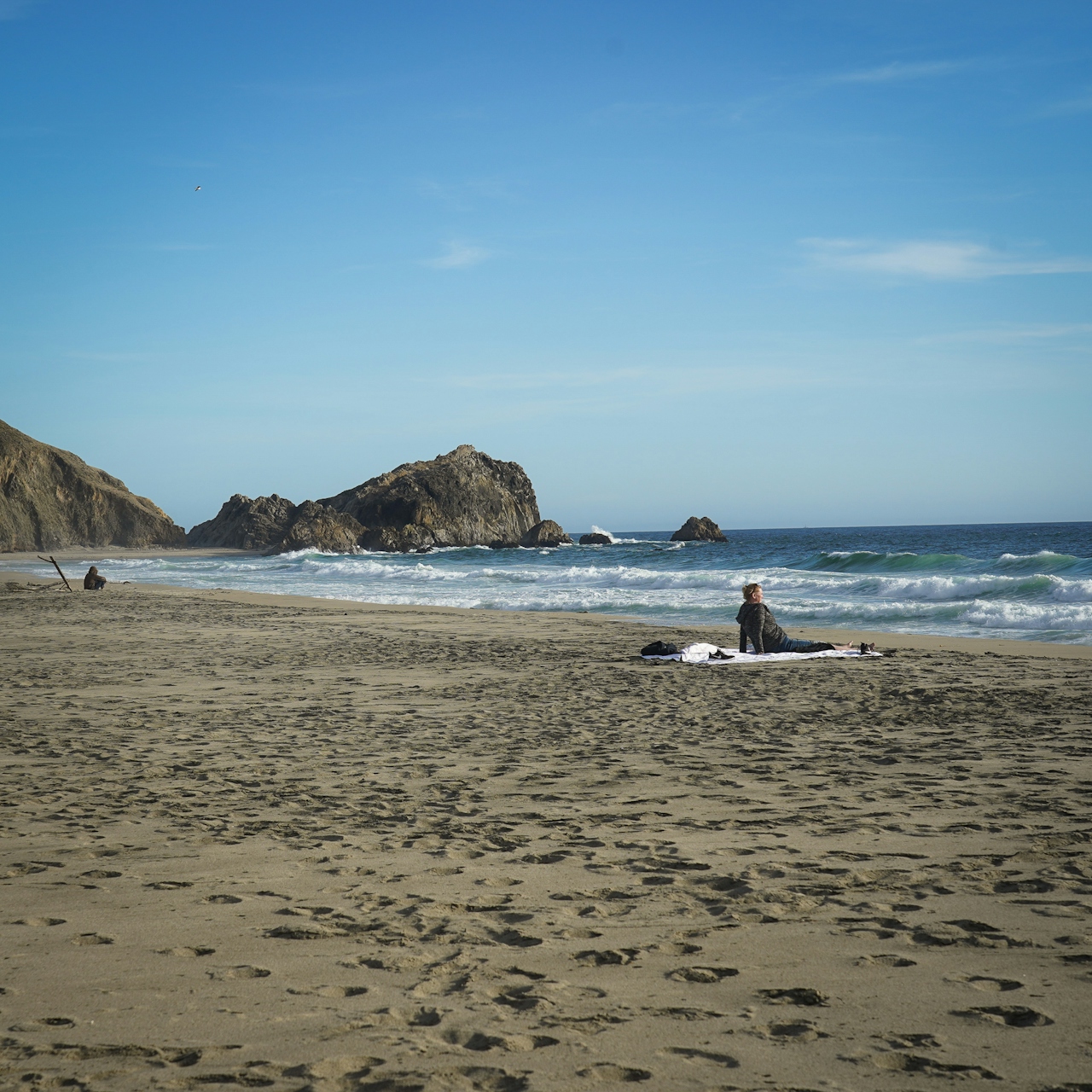 Hiker sitting and looking out to the waves at McClures Beach in Point Reyes National Seashore