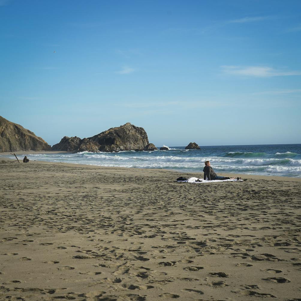 Hiker sitting and looking out to the waves at McClures Beach in Point Reyes National Seashore