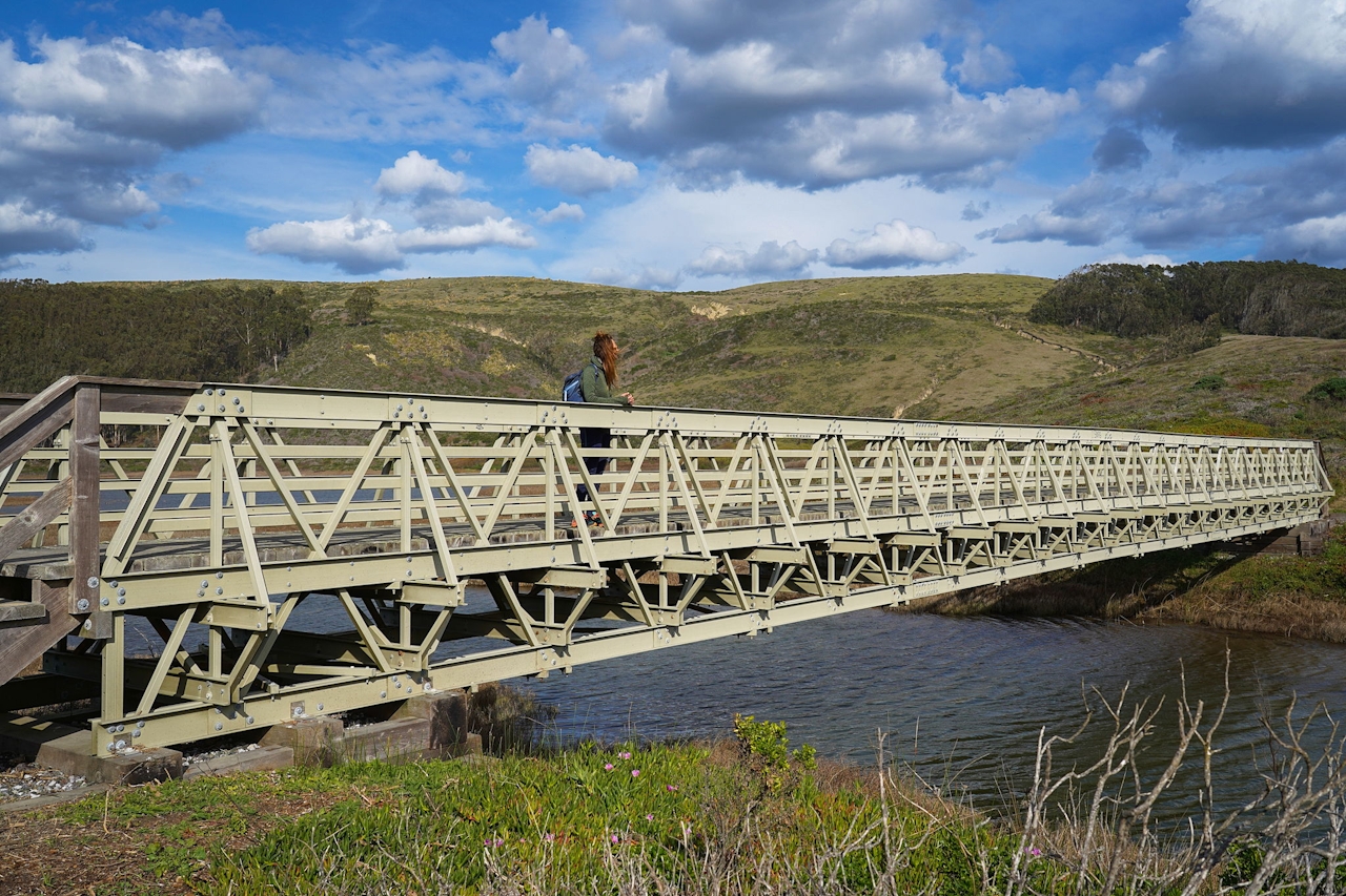 Woman stopped on a pedestrian bridge crossing at Pescadero Marsh Natural Preserve