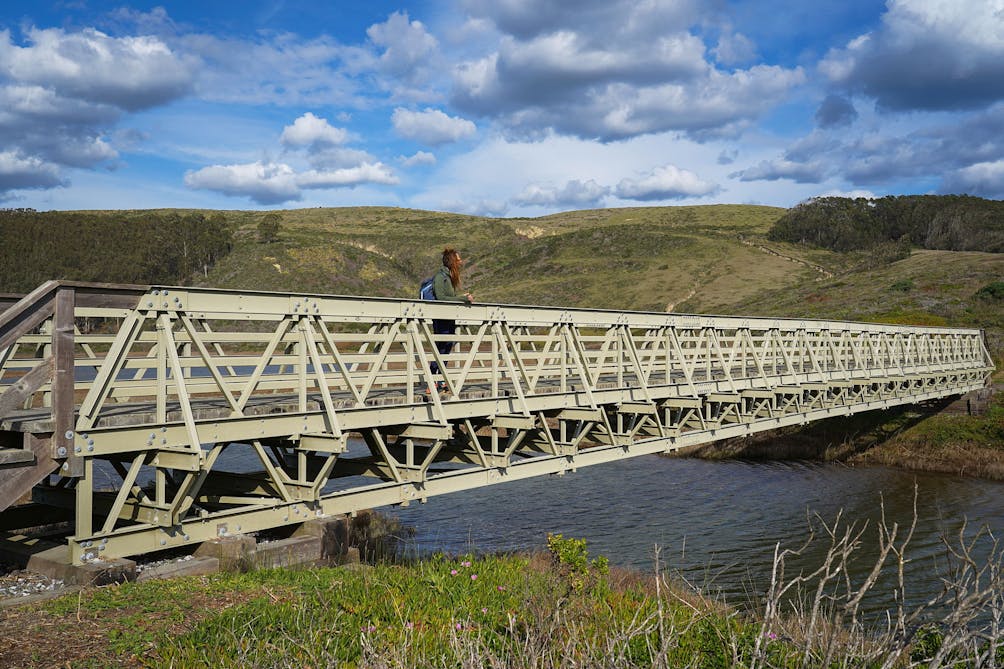 Woman stopped on a pedestrian bridge crossing at Pescadero Marsh Natural Preserve