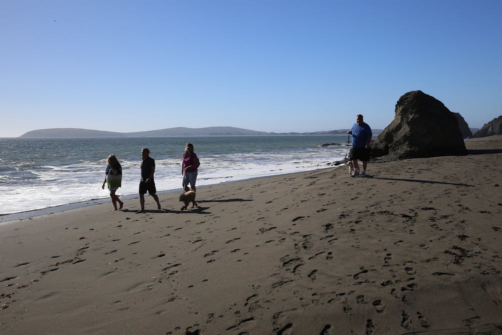 People walking on the sand near the ocean at Pinnacle Gulch beach near Bodega 