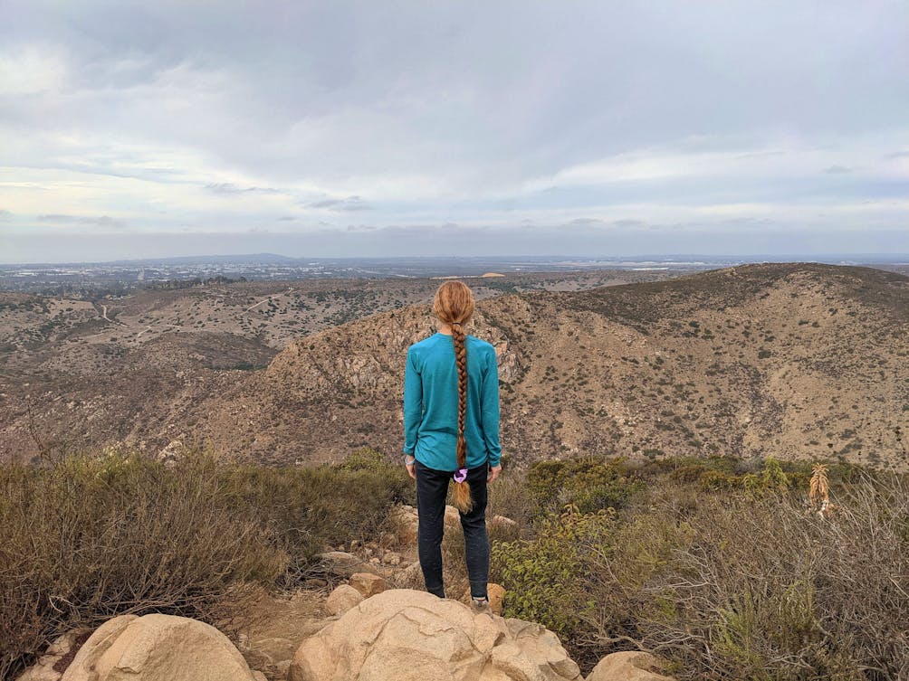 Woman standing at Kwaay Paay peak in San Diego County 