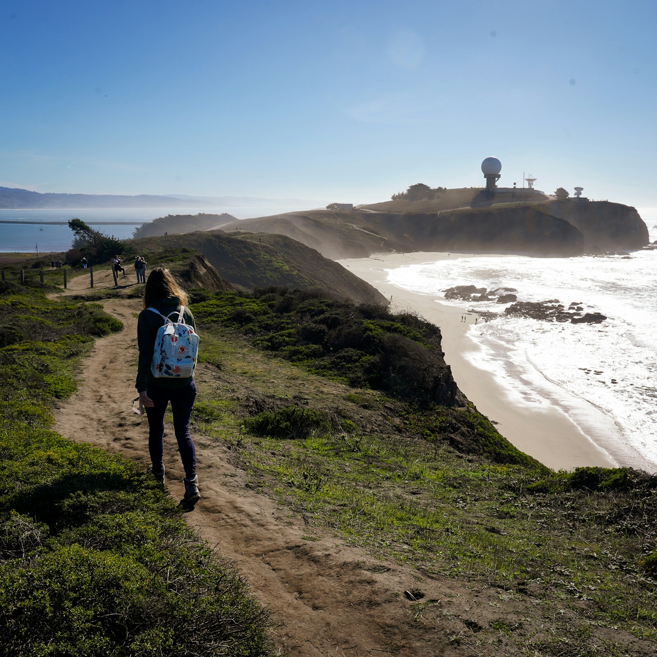 Woman hiking along Pillar Point Bluff towards the Pillar Point Air Force Station 