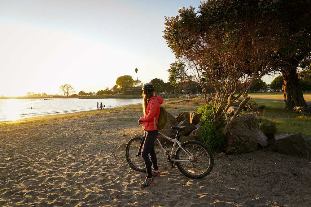 Woman on a bike at a beach in Alameda