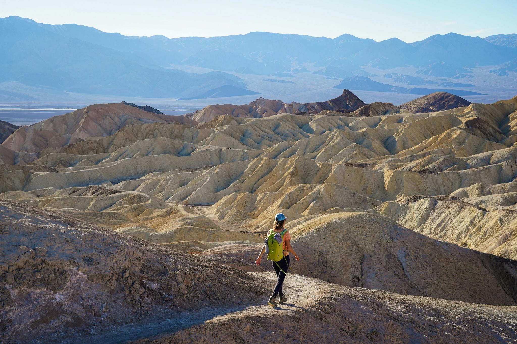 Woman hiking the Badlands Trail in Golden Canyon at Death Valley National Park 