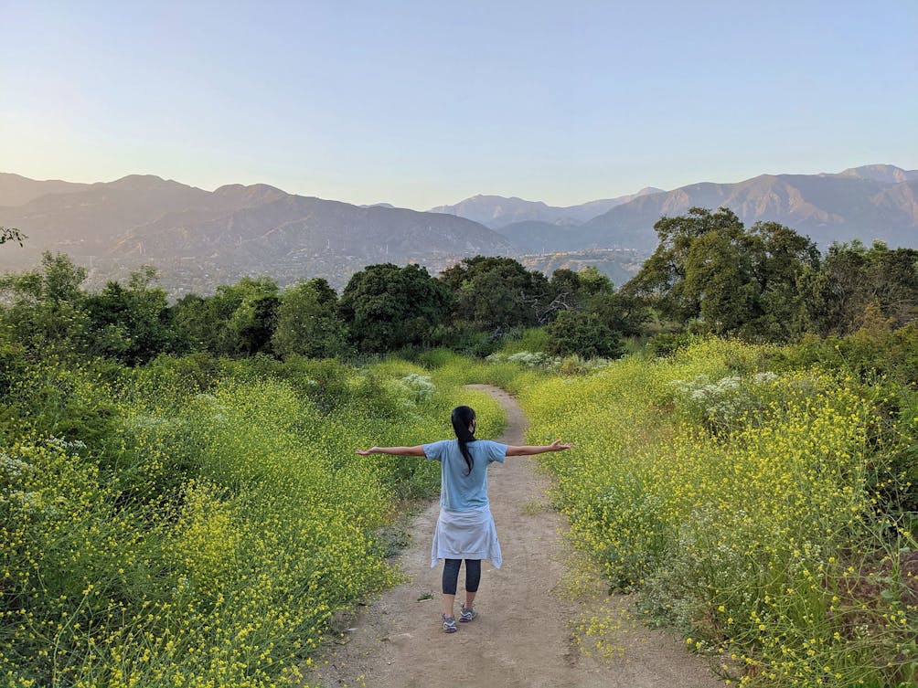 Hiker with outstretched arms to welcome the mountain scenery at Cherry Creek Canyon Park in LA