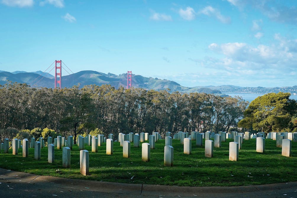 Rows of tombstones with the Golden Gate Bridge in the background at San Francisco National Cemetery 