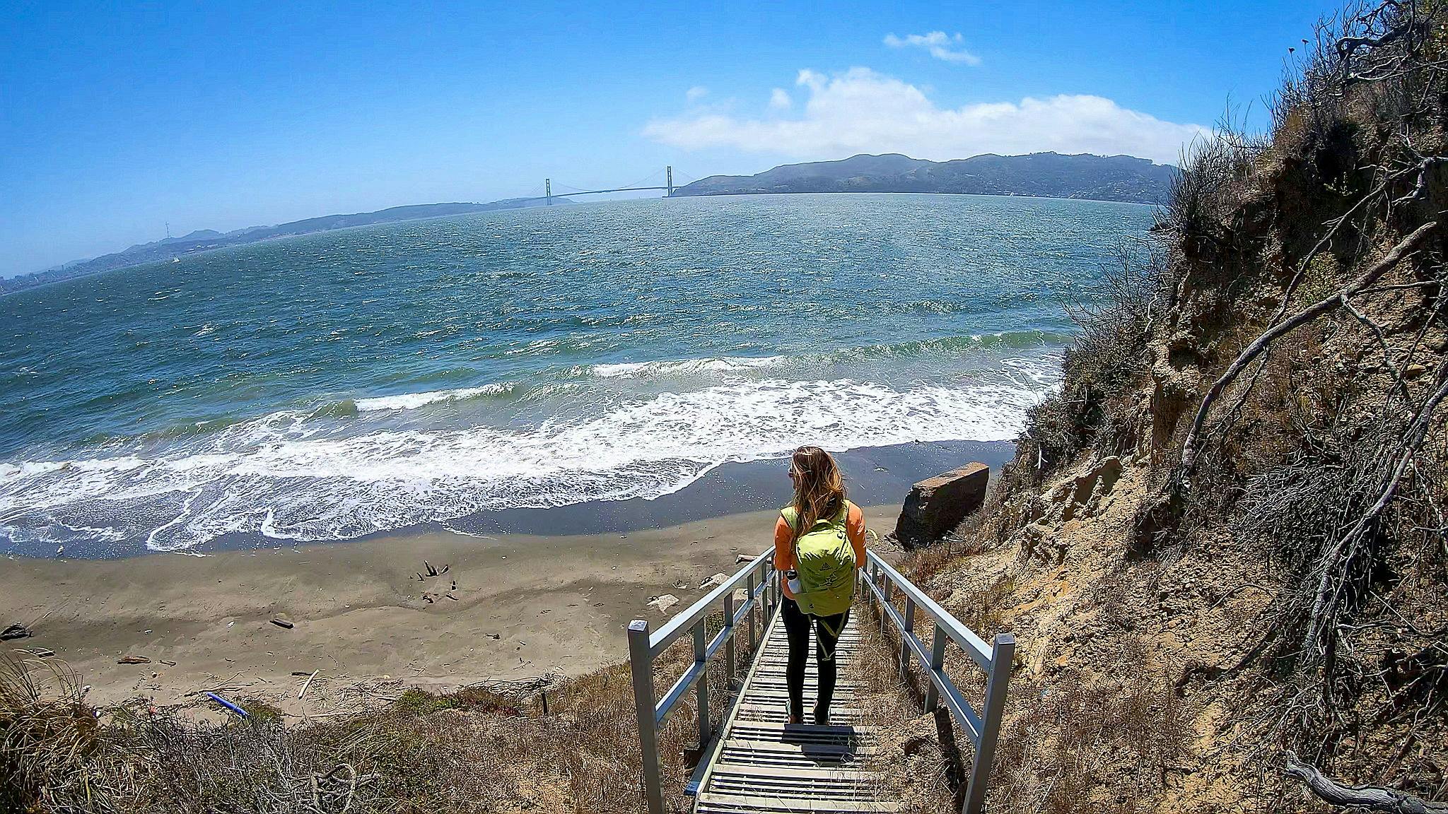 Woman hiking down stairs to Perles Beach on Angel Island State Park in the San Francisco Bay Area