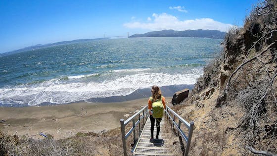 Woman hiking down stairs to Perles Beach on Angel Island State Park in the San Francisco Bay Area