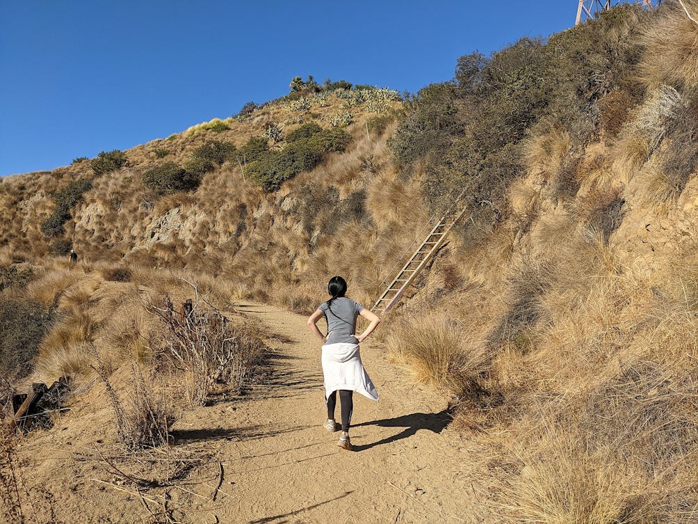 Woman hiking by a ladder on a trail in Trebek Open Space 