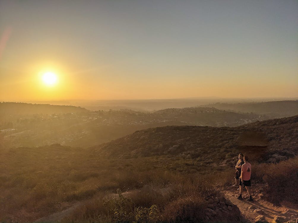 Two friends descending a hiking trail at sunset in Mission Trails Regional Park San Diego 