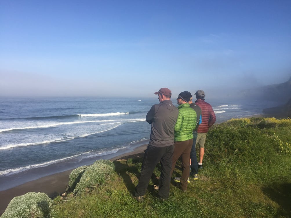 Three friends on the bluff trail at Wildcat Camp overlooking the beach and ocean in Point Reyes National Seashore 