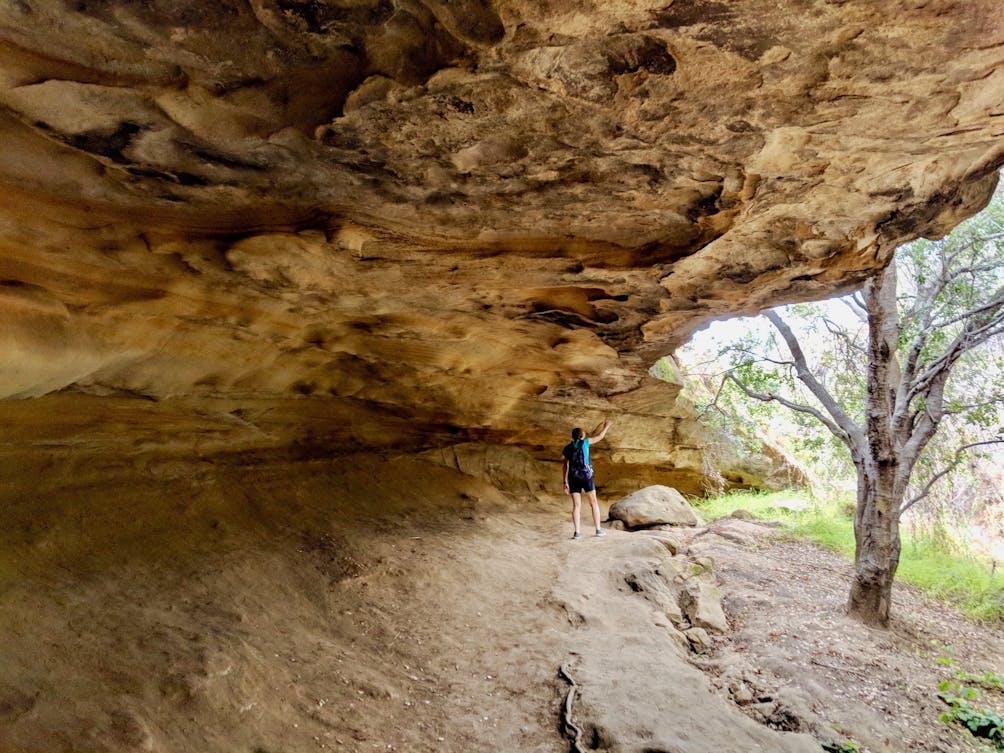 Hiker under Dripping Cave at Alison and Wood Canyons Wilderness Park 