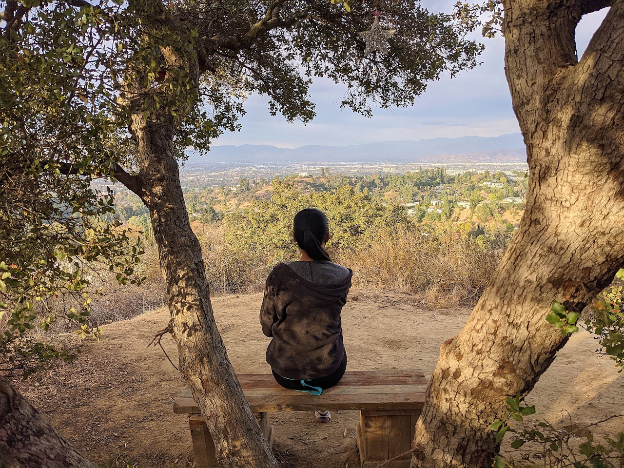 Woman sitting at bench in Fryman Canyon overlooking the San Fernando Valley view