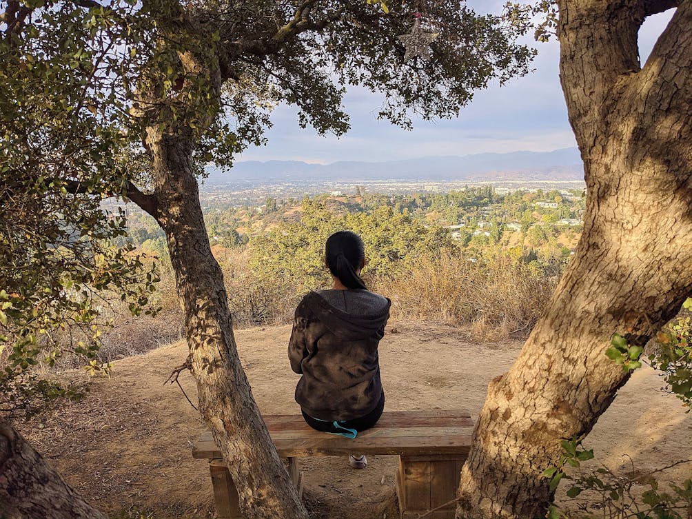 Woman sitting at bench in Fryman Canyon overlooking the San Fernando Valley view