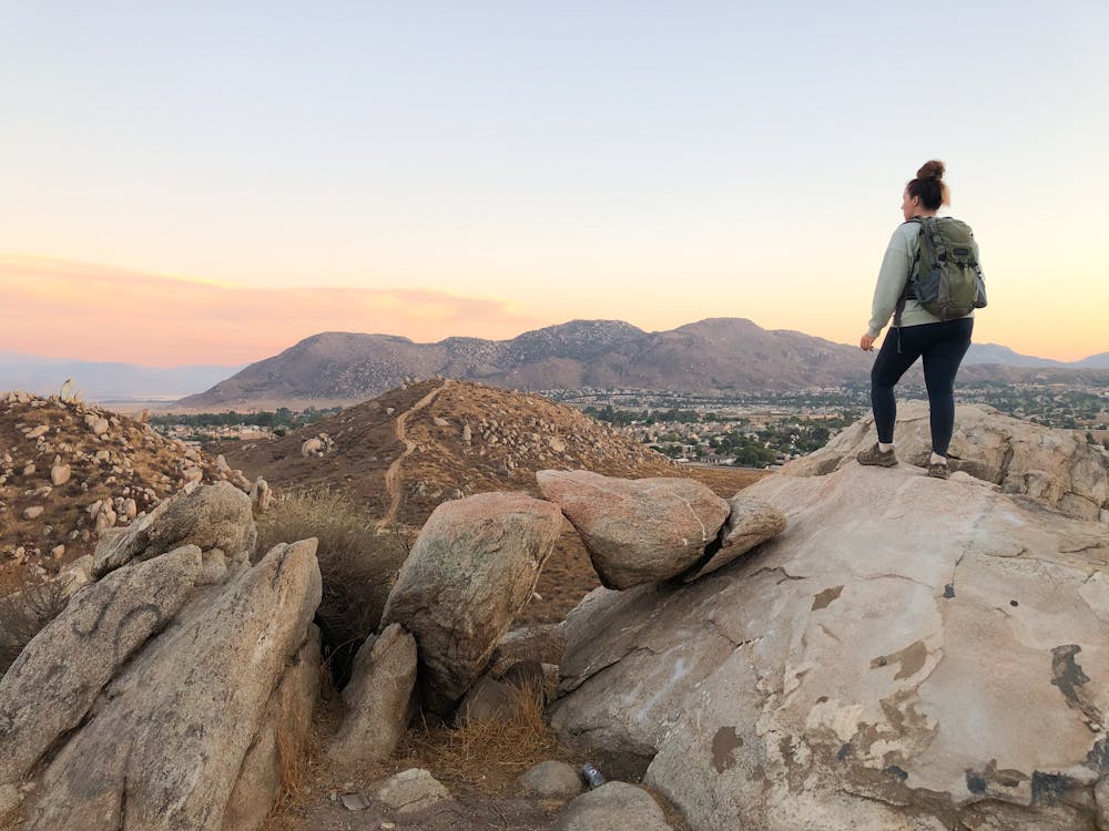 Woman standing on rocks overlooking mountain scenery at sunset in Los Angeles County at Cold Creek Trail in Moreno Valley 