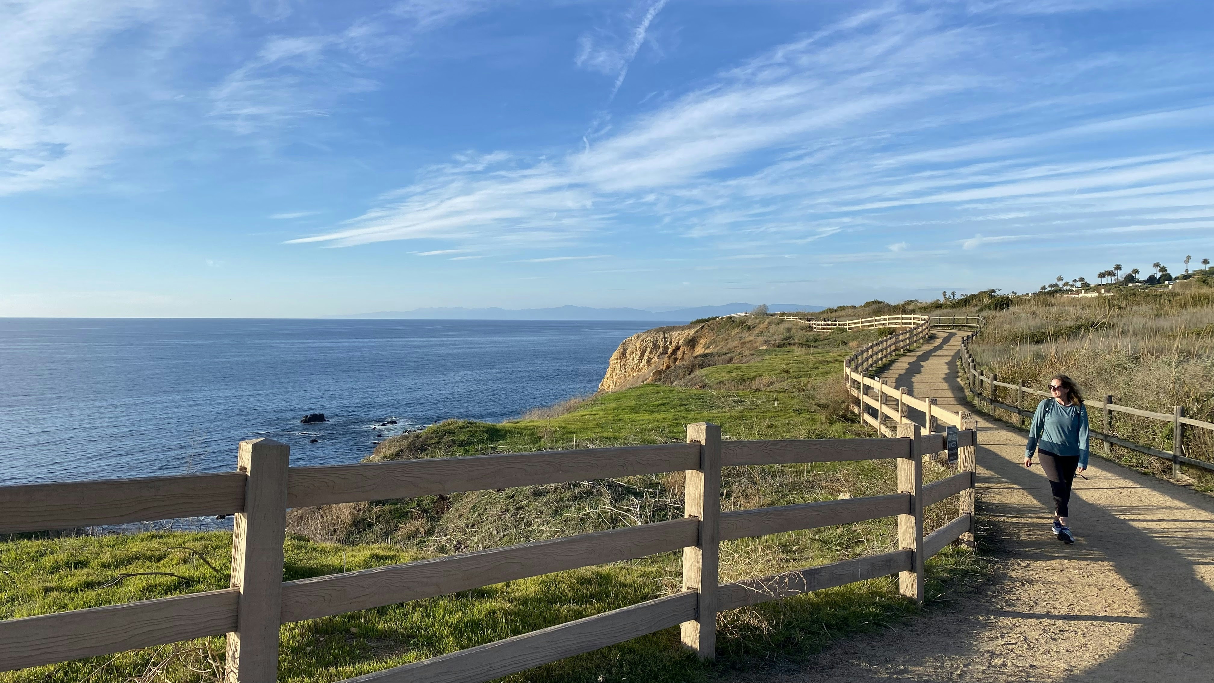 Woman hiking along the Vicente Bluffs Trail in Rancho Palos Verdes Southern California. The ocean is paralleling the trail.