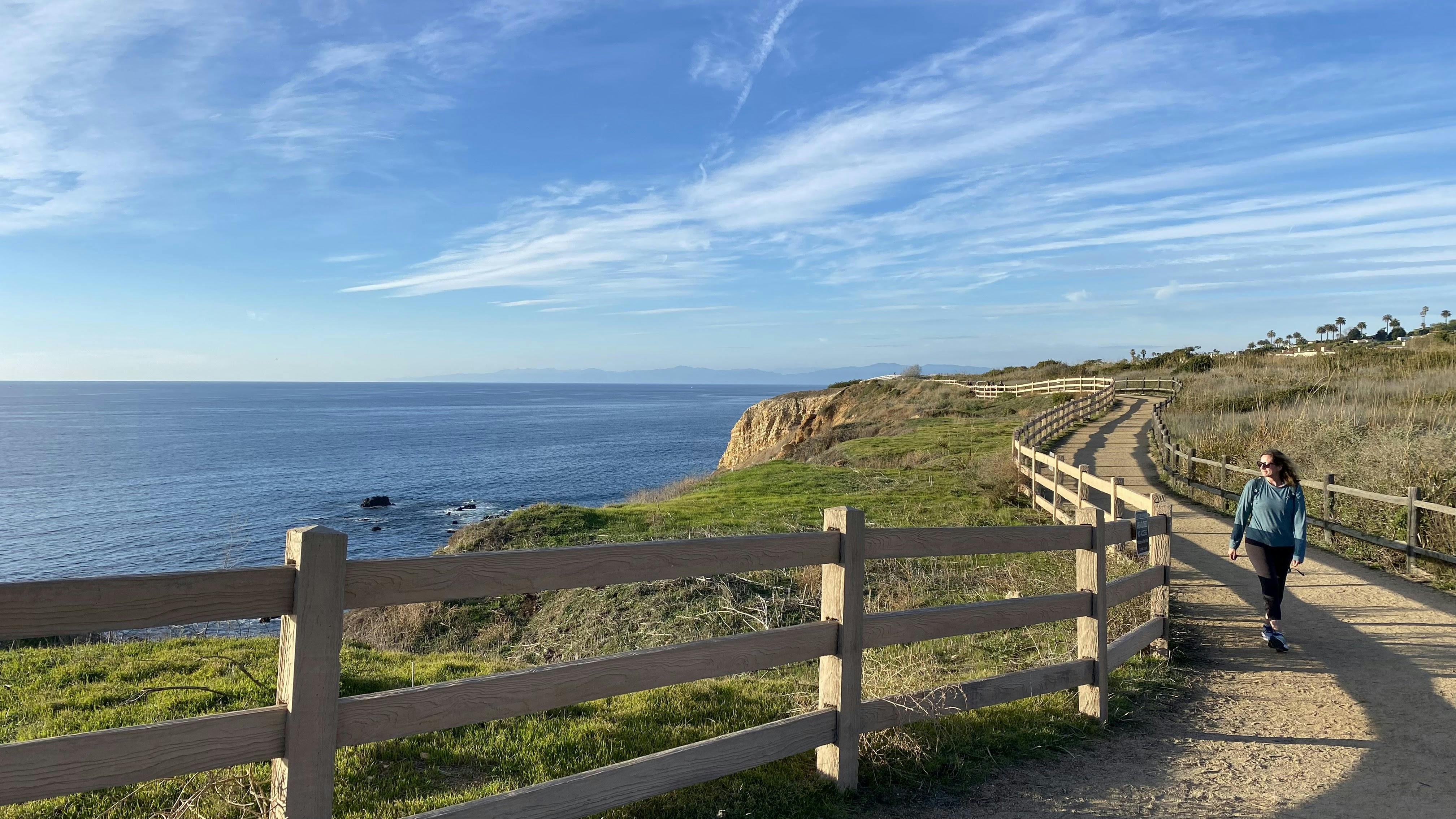 Woman hiking along the Vicente Bluffs Trail in Rancho Palos Verdes Southern California. The ocean is paralleling the trail. 