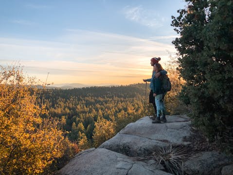 Woman standing on hiking trail in Idyllwild, overlooking sunset and mountain scenery