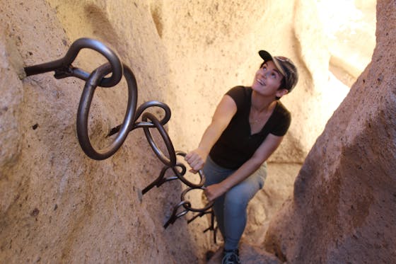 Woman hiking up canyon wall using wall rings as an assist in Mojave Desert on Hole-in-the-Wall hike