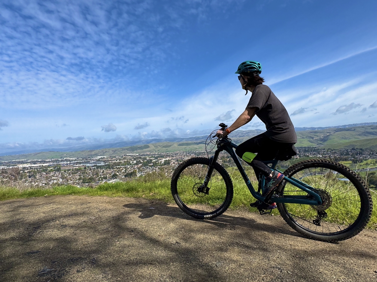 Mountain bike rider on Coyoke Peak Trail overlooking the Silicon Valley and Santa Clara Valley below, with the Santa Cruz Mountains in the background