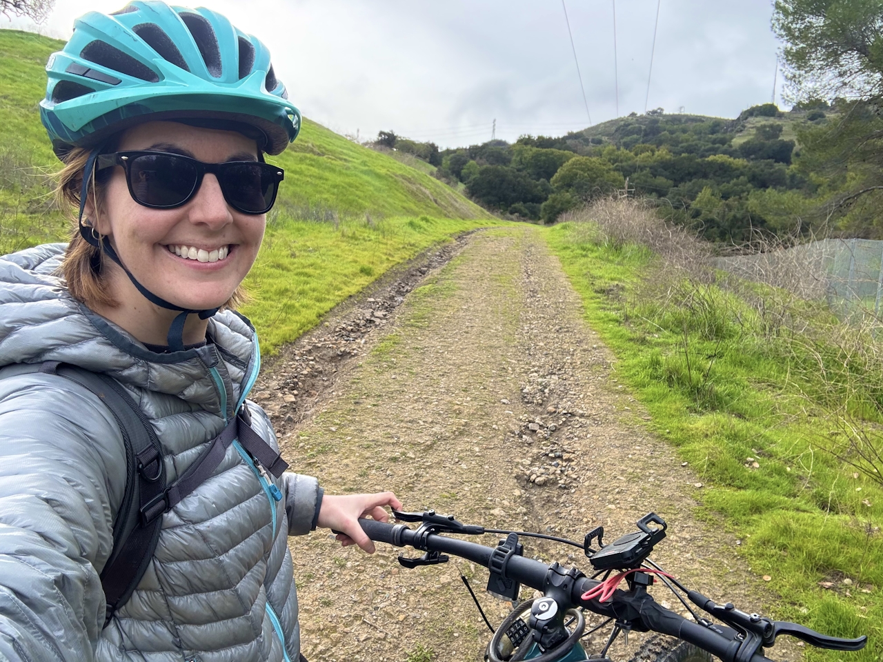 Bike rider smiling at camera on a wide open dirt trail on Coyote Peak Trail in Santa Teresa County Park in San Jose 