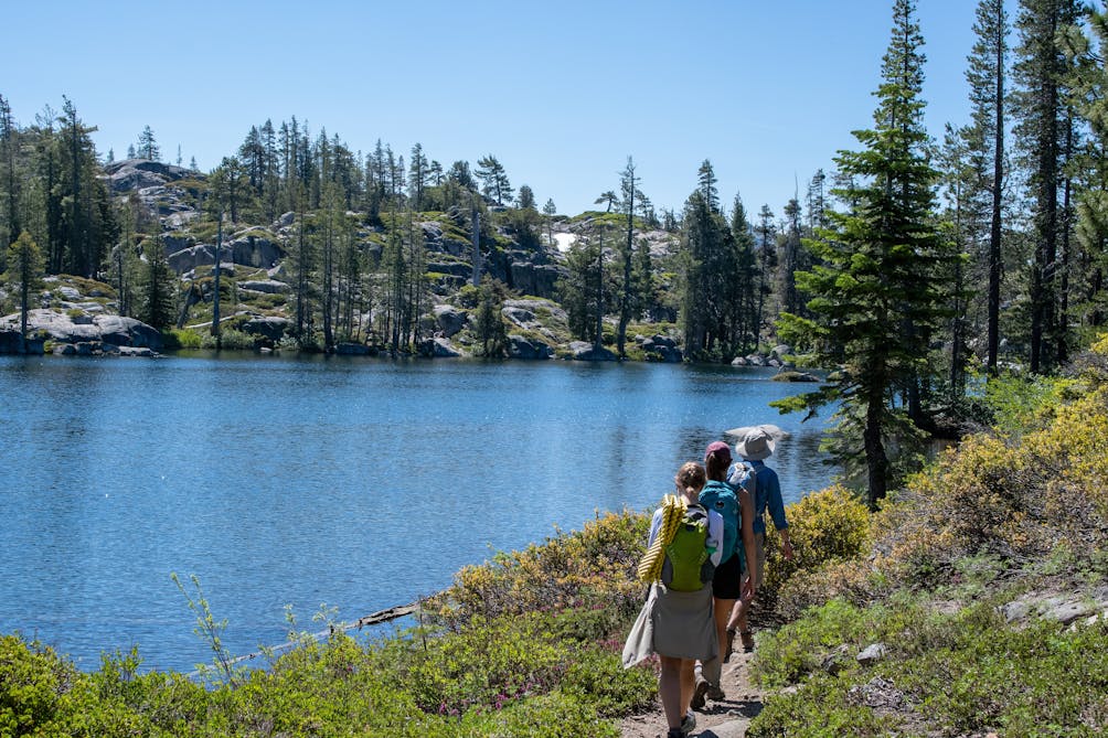 Backpackers walking next to Loch Leven Lakes in Tahoe National Forest 