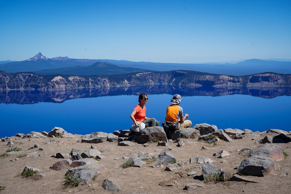 Hikers sitting and overlooking Crater Lake at Garfield Peak in Crater Lake National Park
