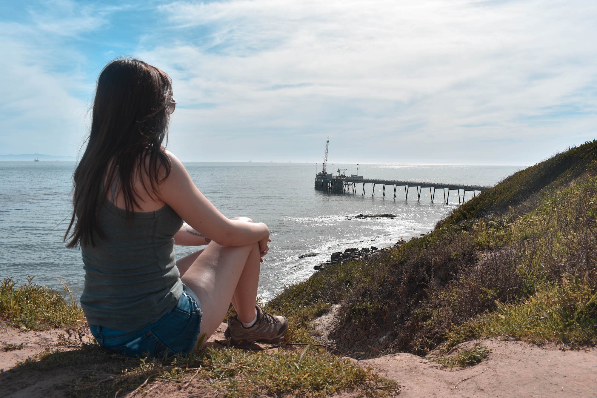 Woman sitting perched on a Bluff overlooking seals at Carpinteria Bluffs Nature Preserve 